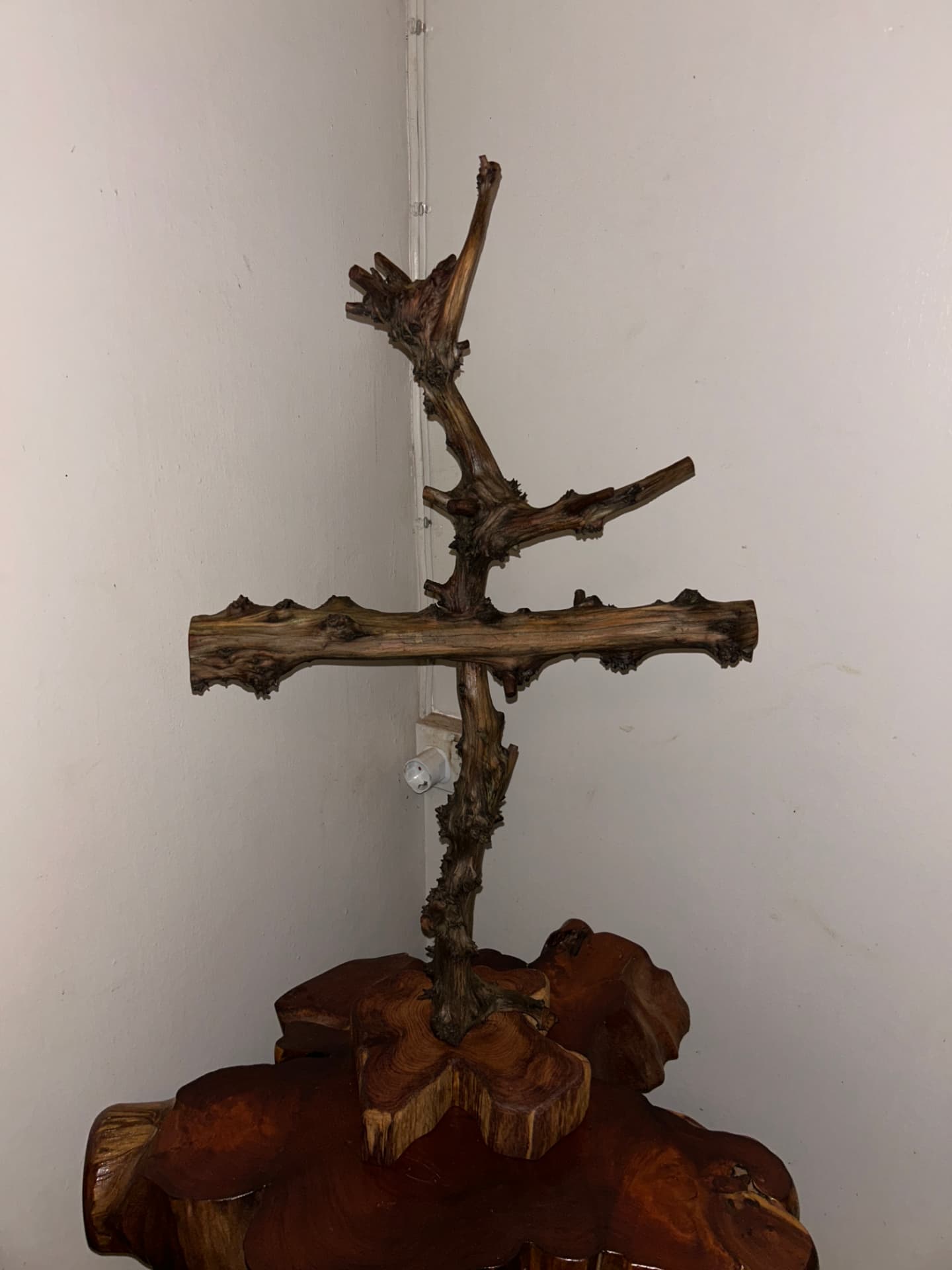 Driftwood cross sculpture mounted on a carved wooden base