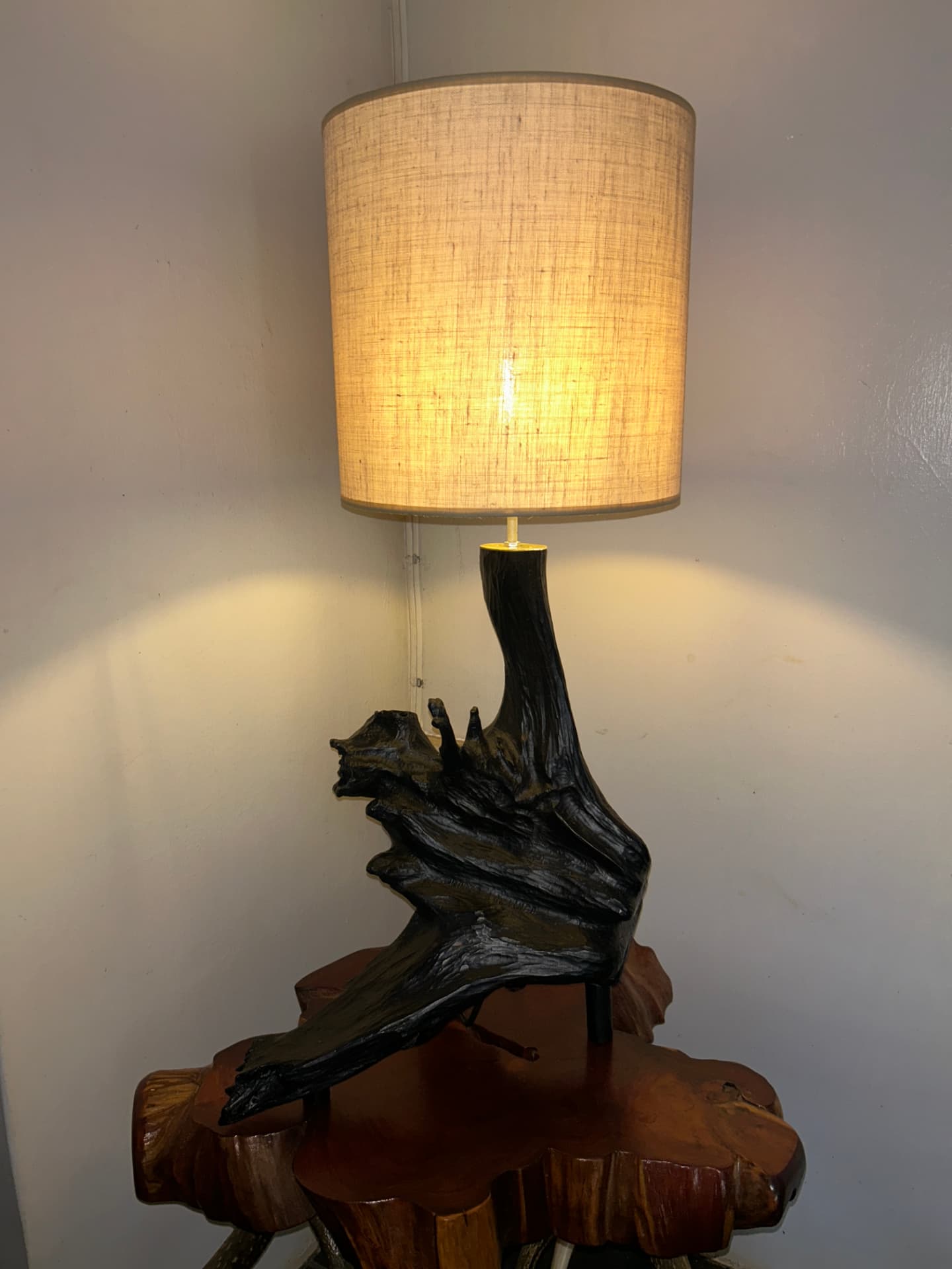 Table lamp carved from dark root wood with a linen shade